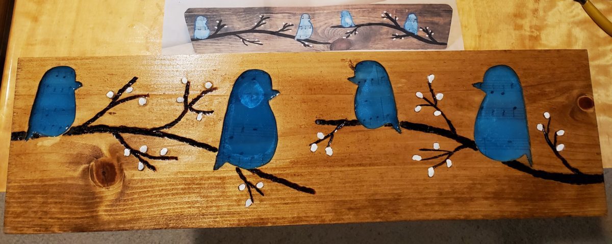 Four blue birds perched on branches carved into a wood plaque created by Chuck Applications Engineer Zuken