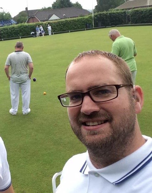 Man dressed in white on a lawn bowls green.