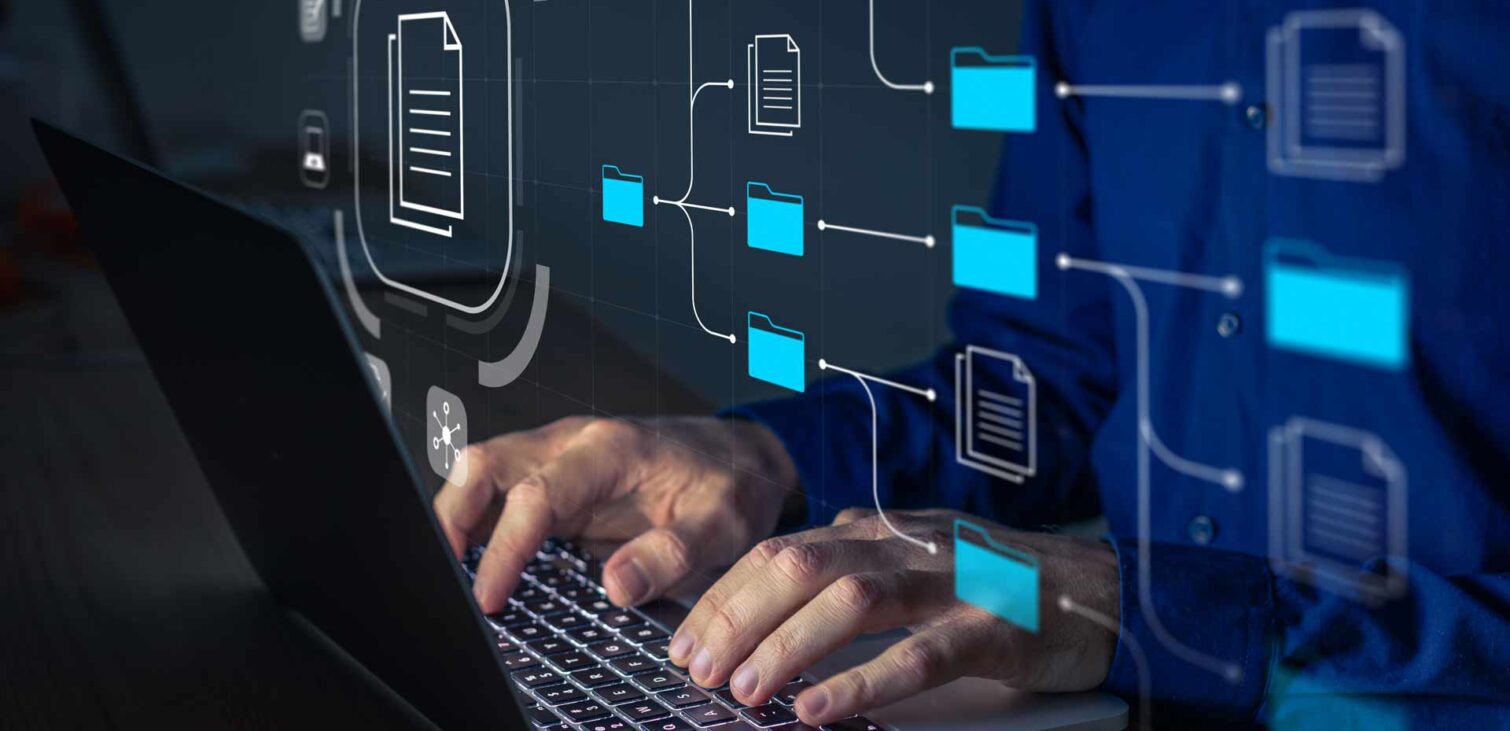 A person typing on a laptop with a digital overlay of interconnected document icons and folders, representing transforms intricate engineering processes into clear, manageable workflows facilitated by GENESYS, Model-based Systems Engineering Software.