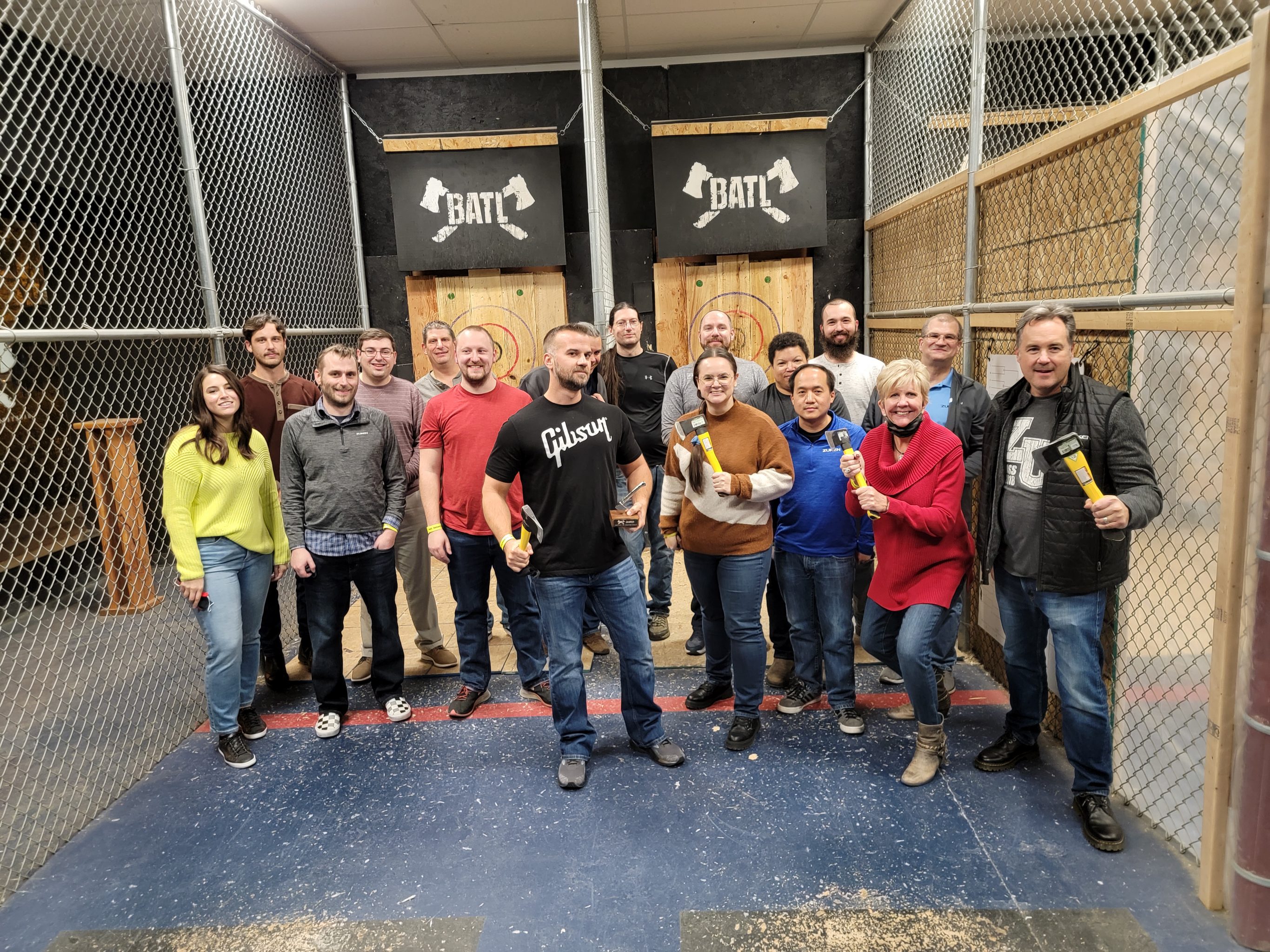 A group of people in a axe throwing cage