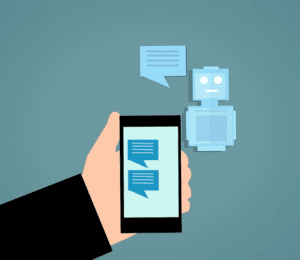 Cartoon hand holding a mobile phone showing text messages. A chatbot is off to the side with a text bubble, apparently interacting with the phone. 