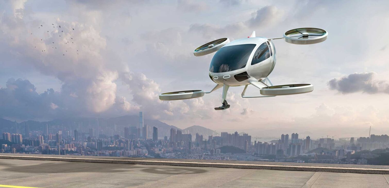 A conceptual Electric Vertical Take Off and Landing Aircraft (eVTOL) hovers over a landing pad near a city