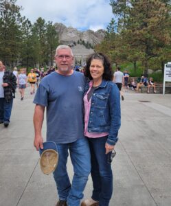 Smiling gentleman and his wife visiting Mount Rushmore National Memorial: Meet Chris