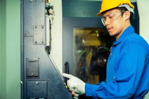 An image of a worker pressing a button controlling a machine.